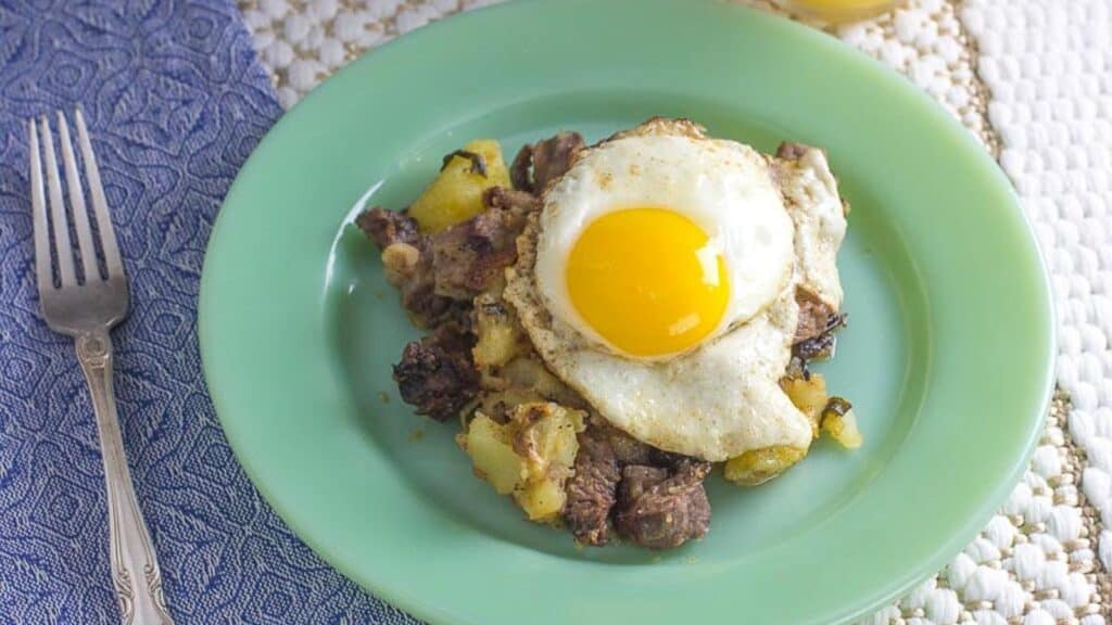 overhead-of-roast-beef-hash-with-friend-egg-and-blue-napkin.