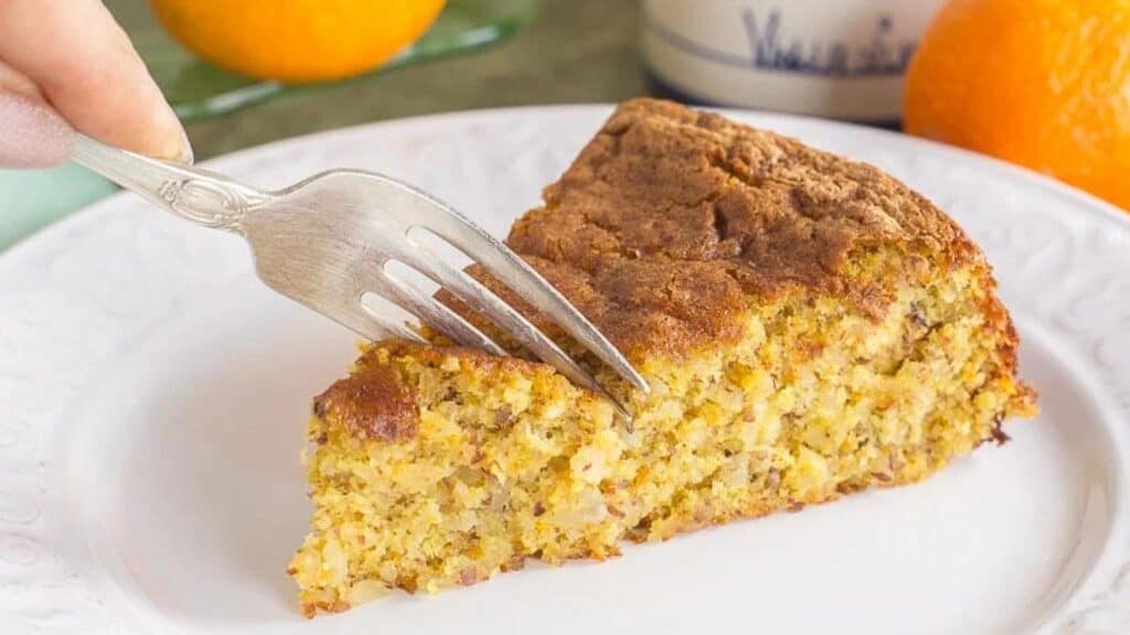 slice-of-orange-almond-cake-on-a-white-plate-fork-cutting-into-it.