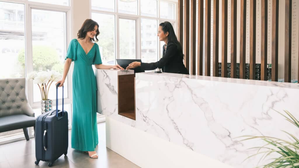 woman checking in to hotel in green dress. 