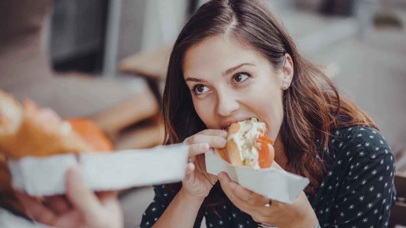 woman eating hot dog.