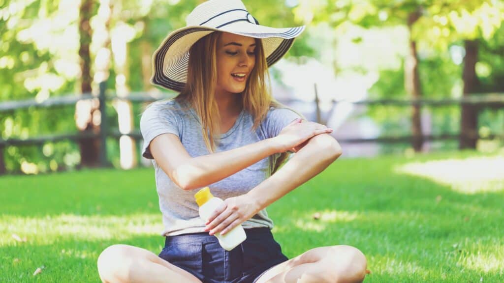 woman in hat applying sunblock.