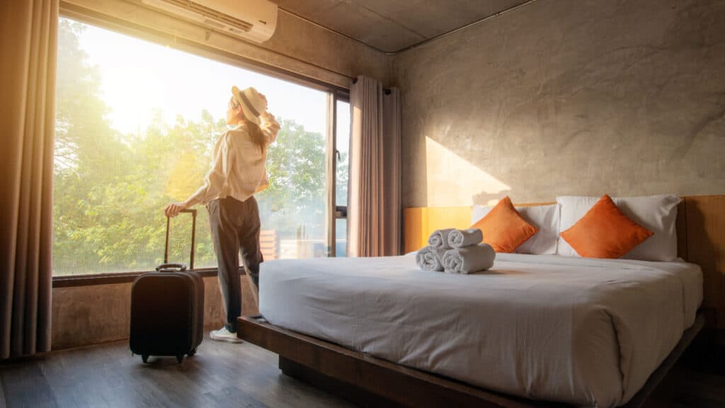 woman in hotel room in front of sunny window.