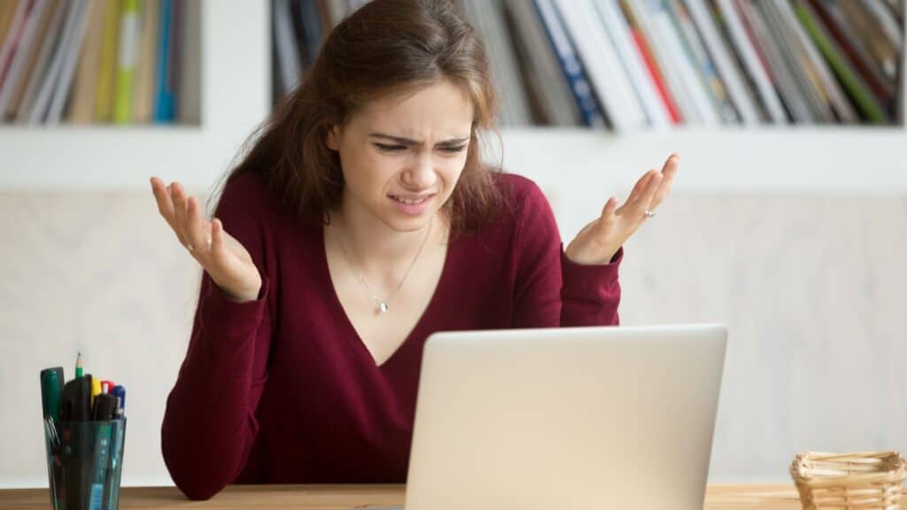 woman looking at computer. Horrified, disgusted, confused.