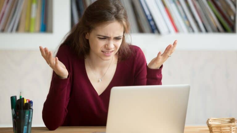 woman looking at computer. Horrified, disgusted, confused.