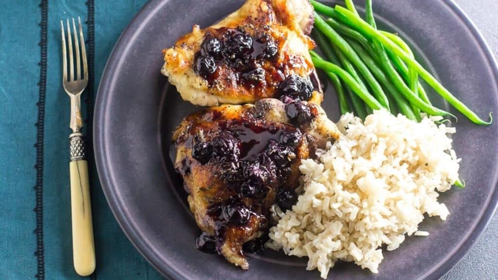 Maple-Balsamic-Chicken-With-Roasted-Blueberries-on-gray-plate-with-rice-and-green-beans-antique-fork-alongside.