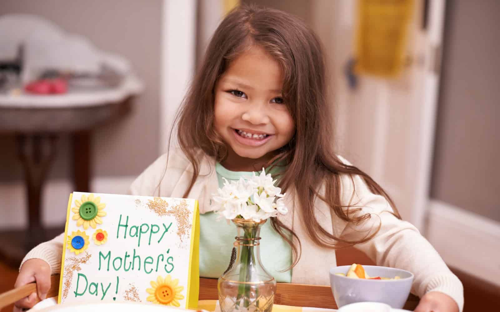 A present for Mom. A little girl bringing her mom breakfast in bed on Mothers Day.