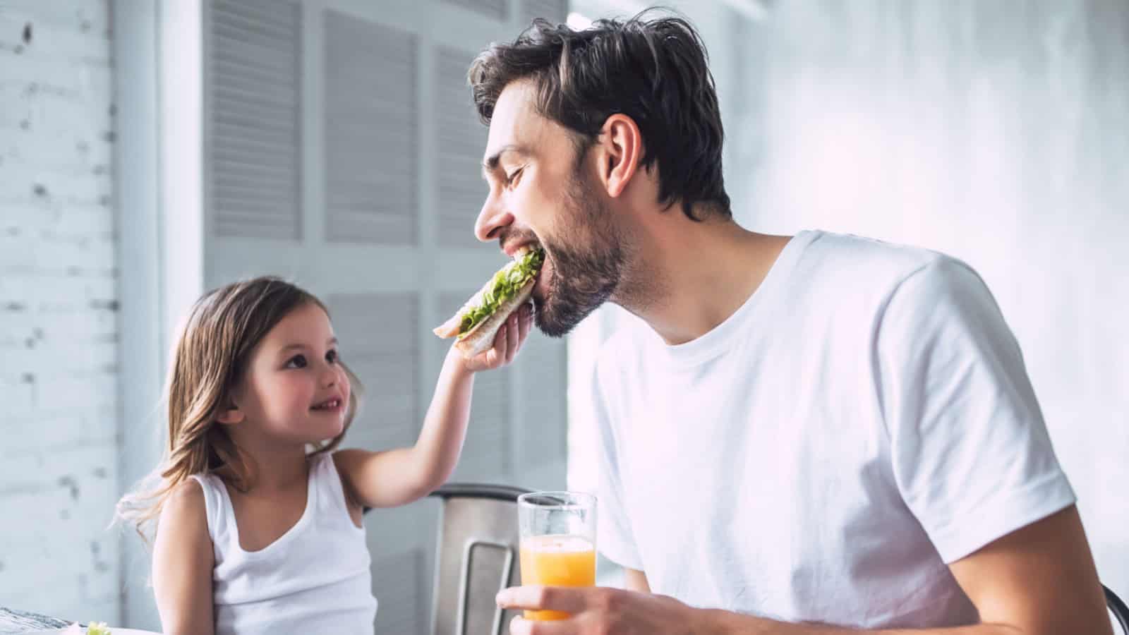 I love you, dad! Handsome young man at home with his little cute girl are having breakfast. Happy Father's Day!