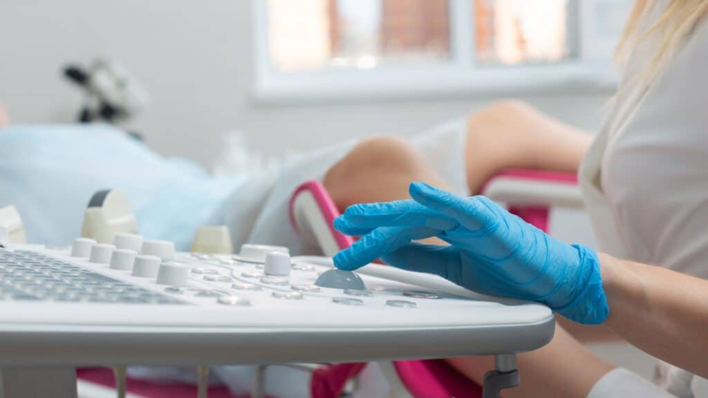 A gynecologist performs an ultrasound diagnostic procedure for a woman lying in a gynecological chair. Pregnancy management, fetal health monitoring