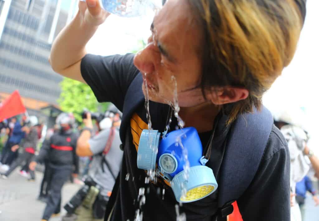man flushing tear gas out his eyes with water