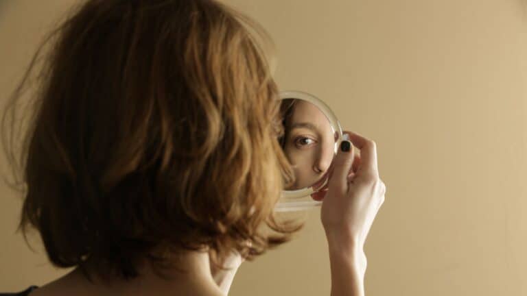 woman looking at herself in hand mirror