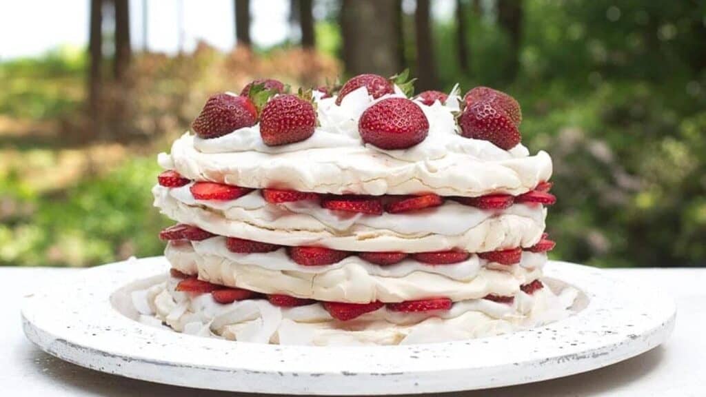 Strawberry-Coconut-Meringue-Cake-on-white-wooden-plate-outside-on-the-deck.