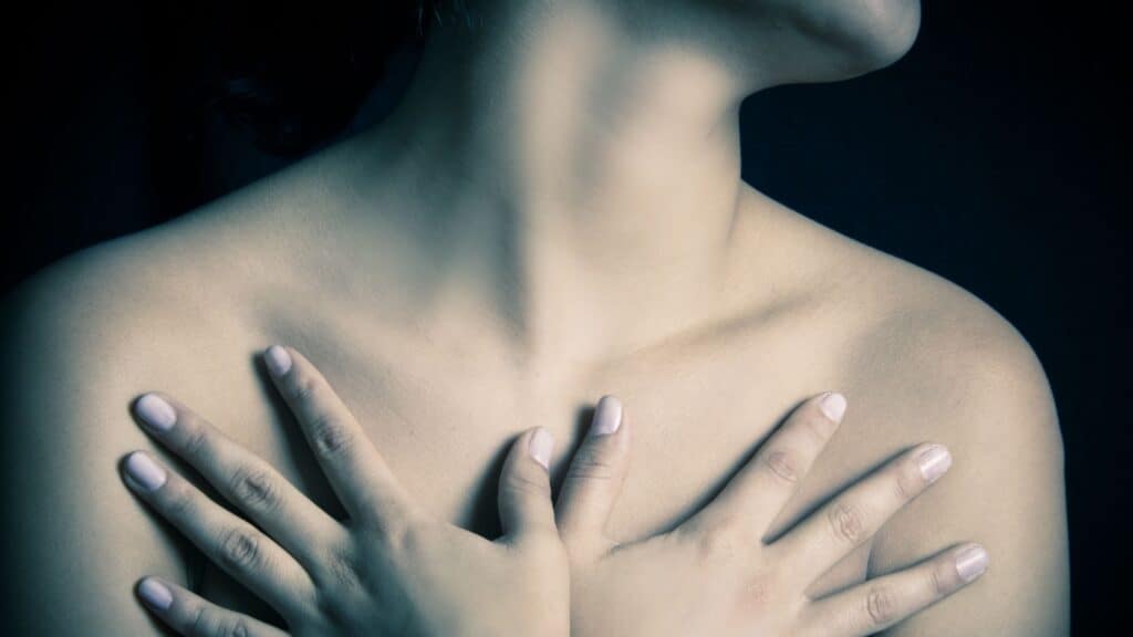 Woman holding chest. 