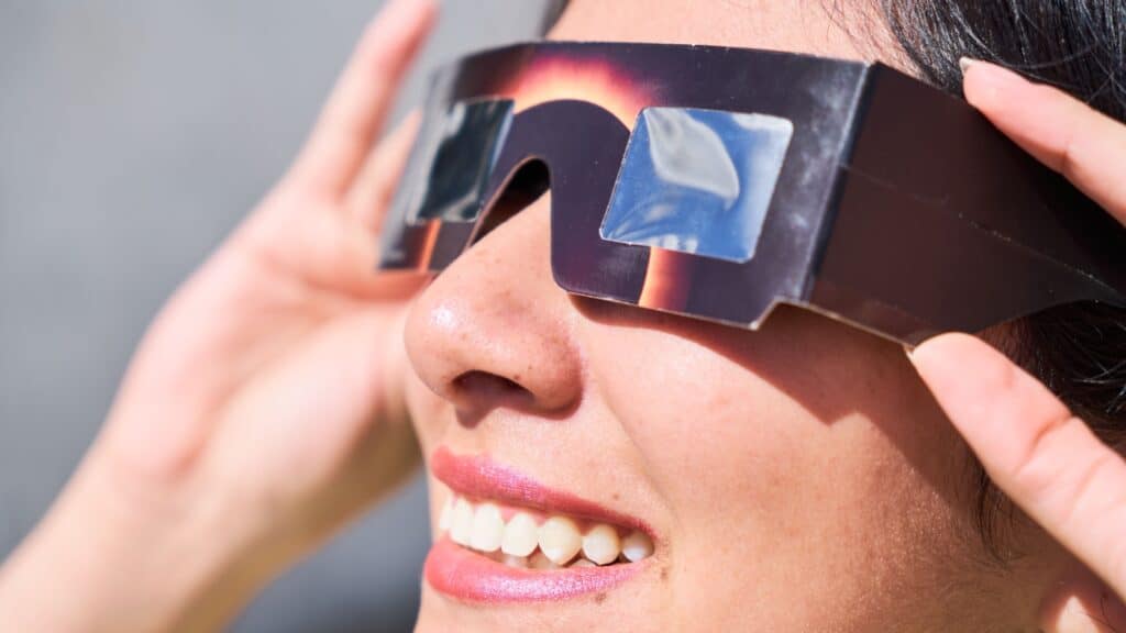 Woman wearing glasses watching solar eclipse.
