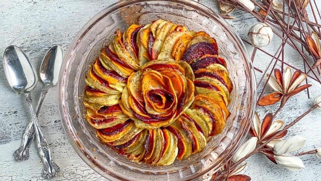 baked-root-vegetable-tian-in-glass-dish-on-white-painted-surface.