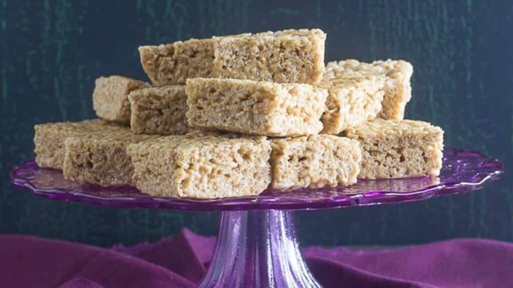 cappuccino-rice-crispy-treats-on-purple-pedestal-with-silver-serving-implement-alongside.