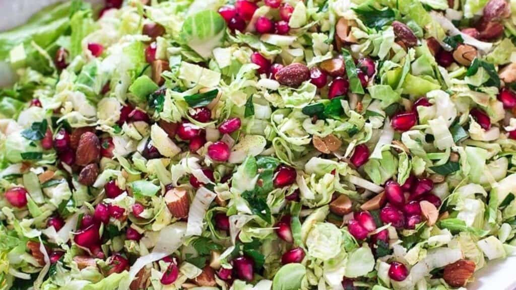 Brussels-sprouts-salad-with-pomegranate-and-almonds-on-white-oval-platter_.