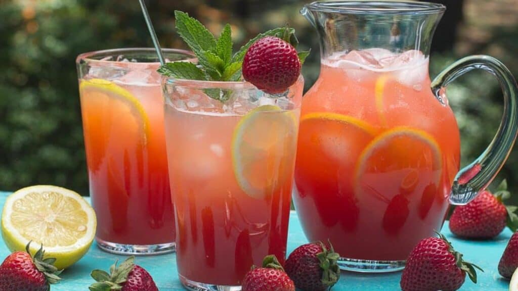 closeup-of-strawberry-lemonade-in-clear-glasses-and-pitcher-with-sprig-of-mint.