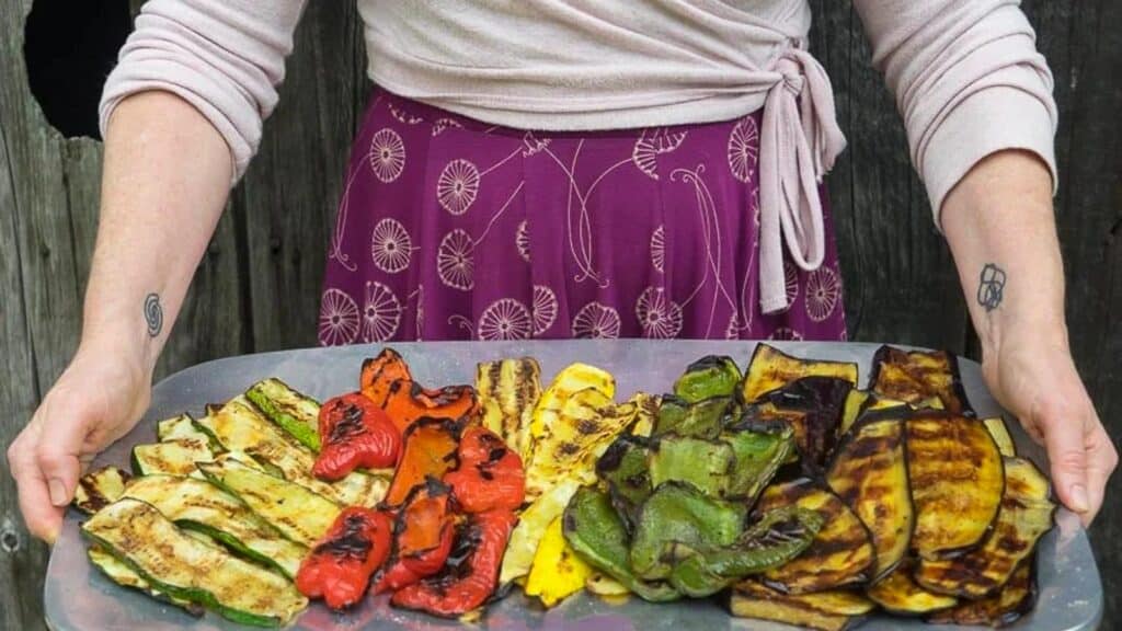 Grilled-vegetables-on-a-large-platter-held-by-a-woman-in-a-dress.