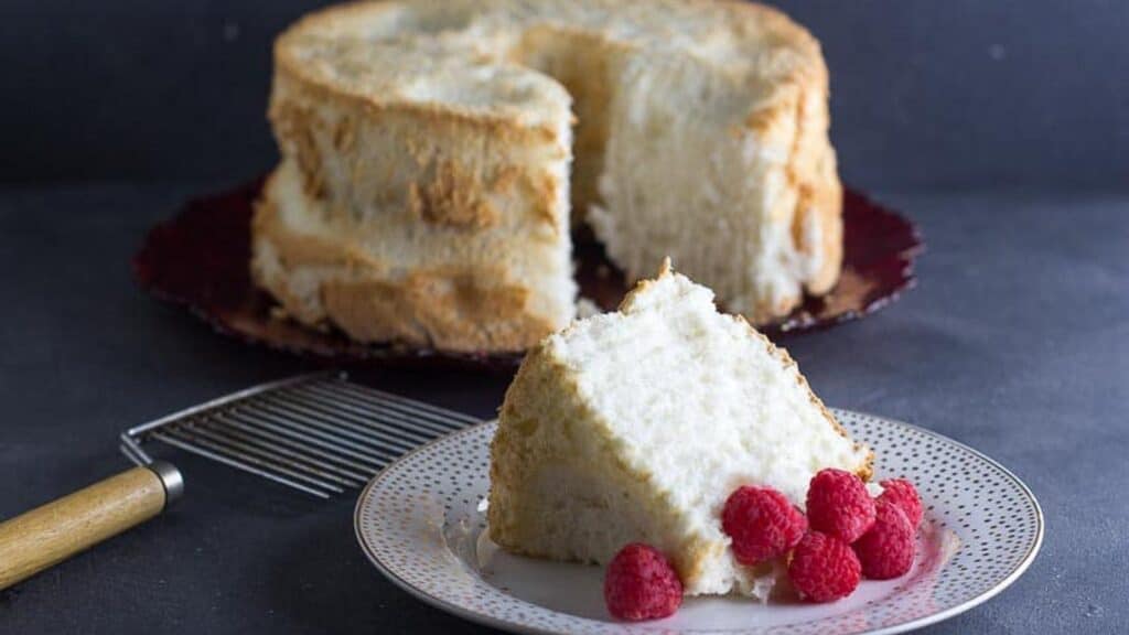 angel-food-cake-in-background-slice-in-foreground.-Angel-Food-Cake-cutter-alongside.