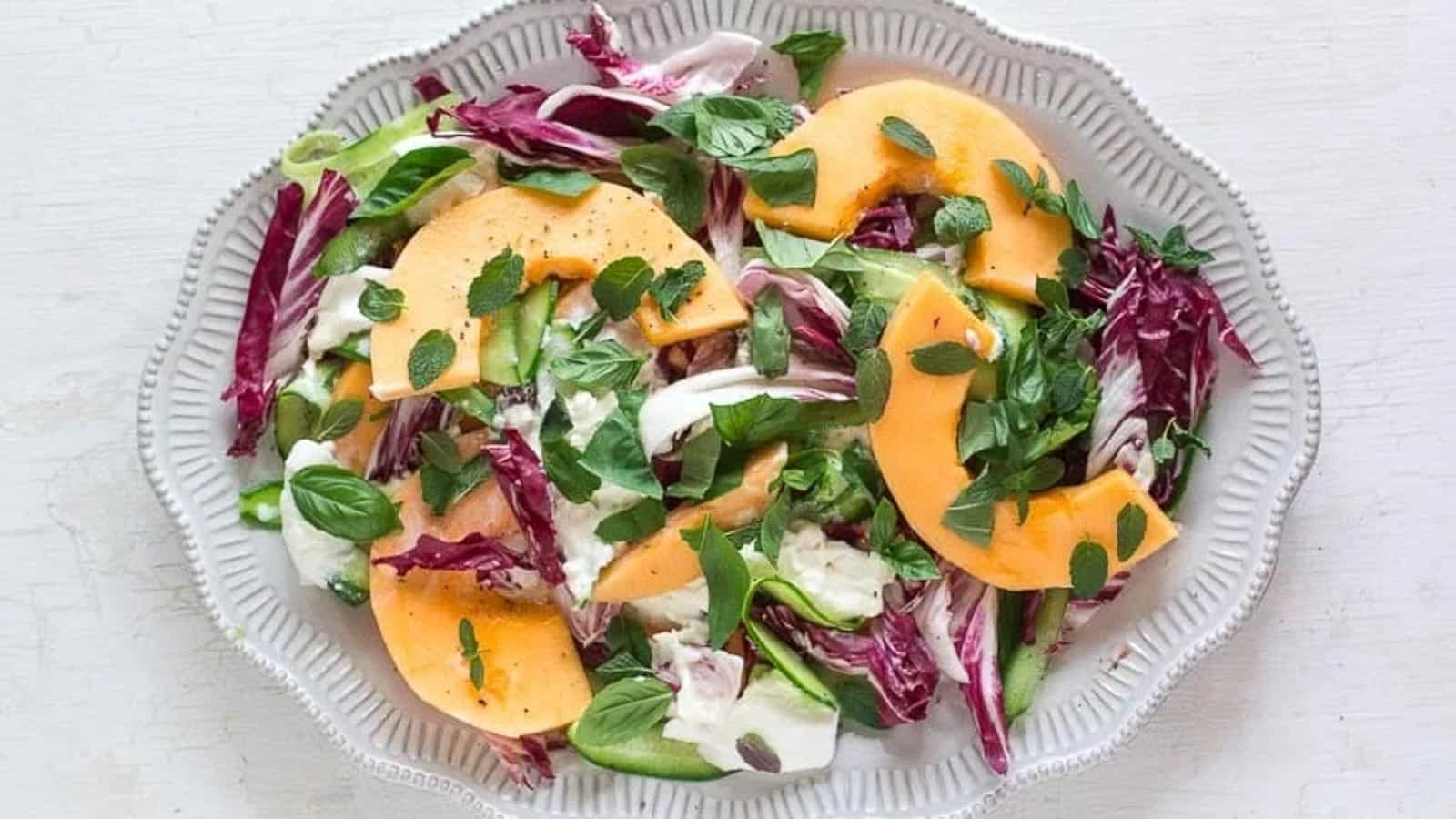 cantaloupe-cucumber-and-burrata-salad-with-herbs-on-a-white-platter-and-white-wooden-surface.