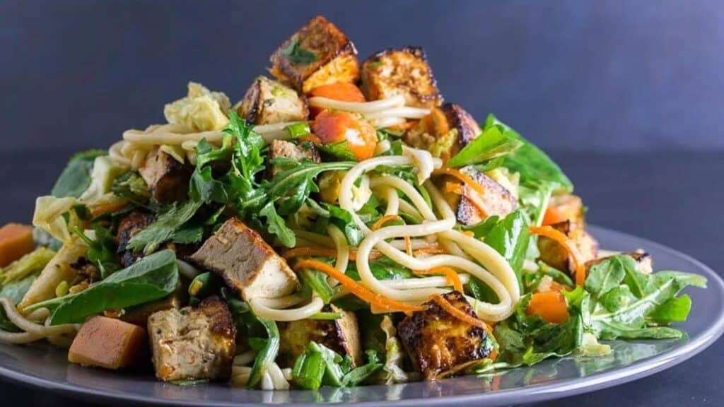 Asian-Tofu-Noodle-Papaya-Salad-on-a-gray-plate-against-dark-background.