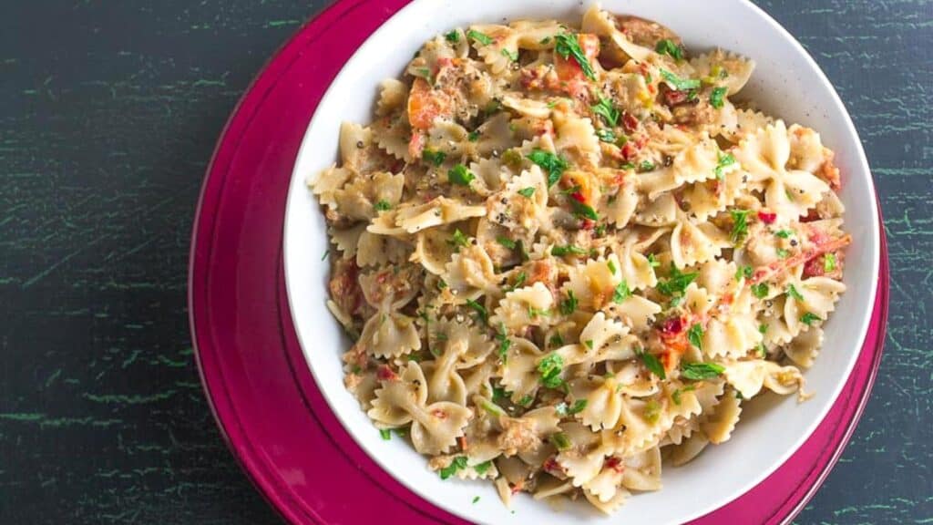 overhead-image-of-Low-FODMAP-Pasta-with-Tuna-Sun-Dried-Tomatoes-in-white-bowl-on-red-plate.