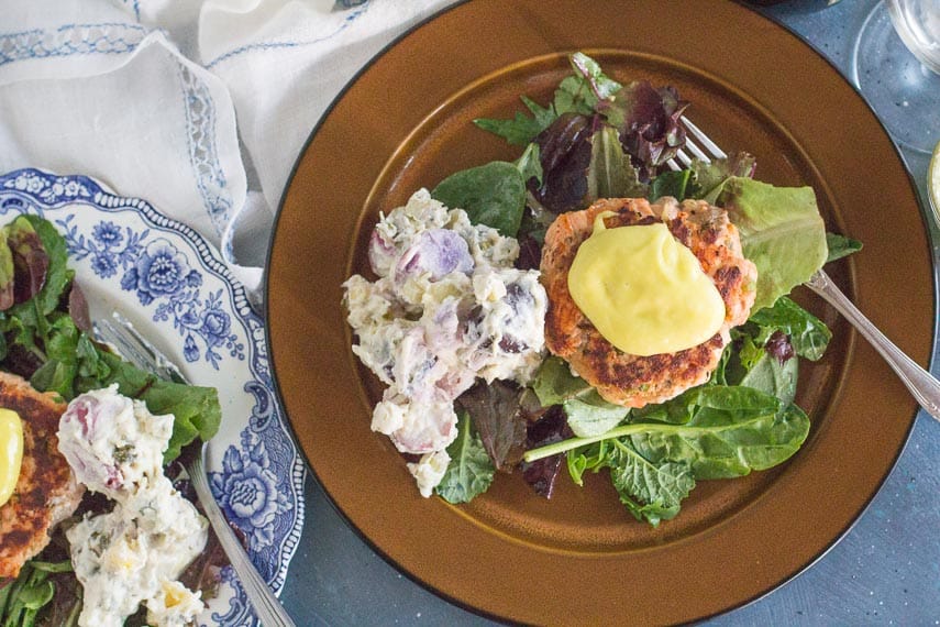 overhead-of-salmon-burgers-with-aioli-on-a-bed-of-greens-and-potato-salad.