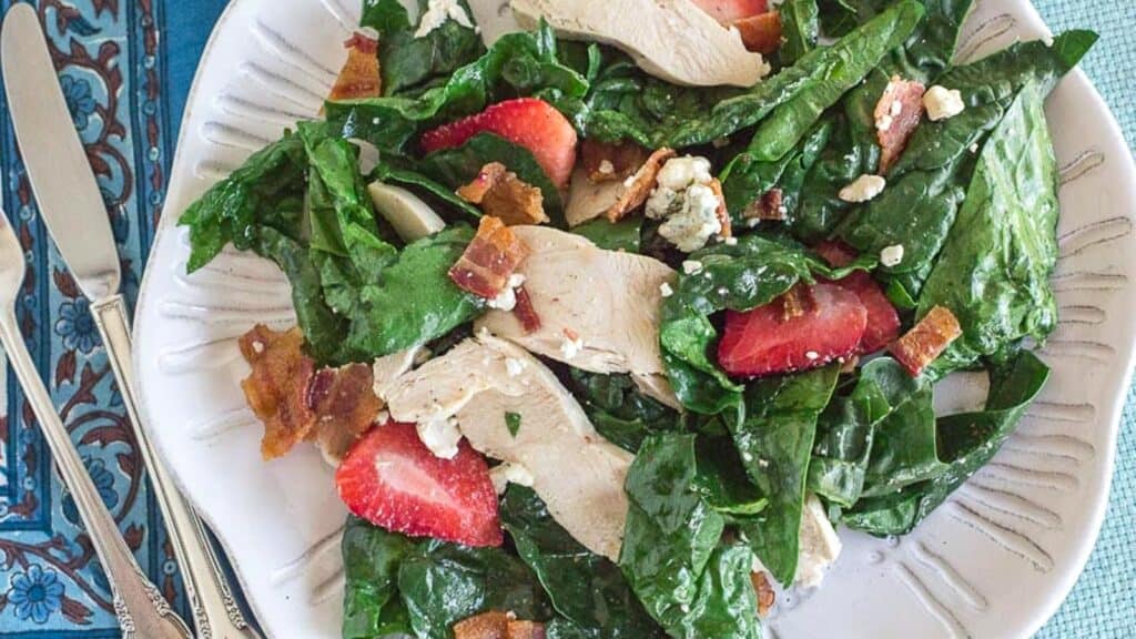 spinach-salad-with-bacon-blue-cheese-and-strawberries-on-a-white-plate-overhead-shot.