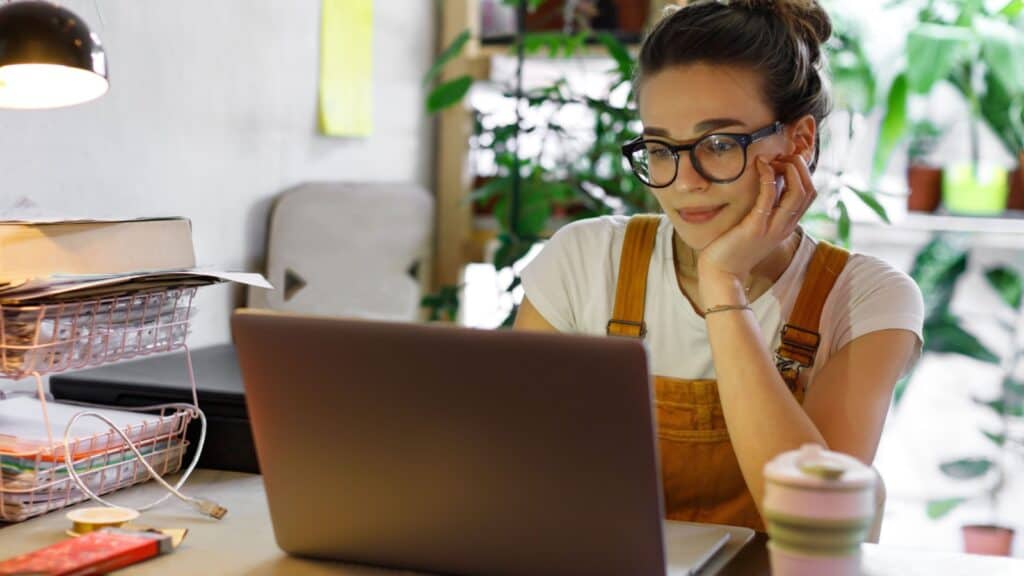 young woman in overalls learning. Computer. Gardener.