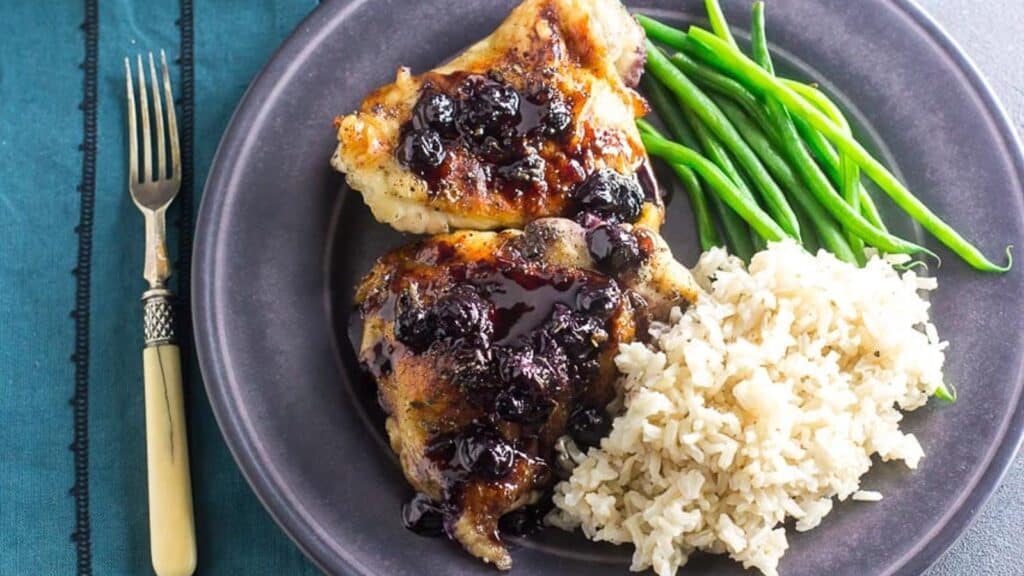 Maple-Balsamic-Chicken-With-Roasted-Blueberries-on-gray-plate-with-rice-and-green-beans-antique-fork-alongside.