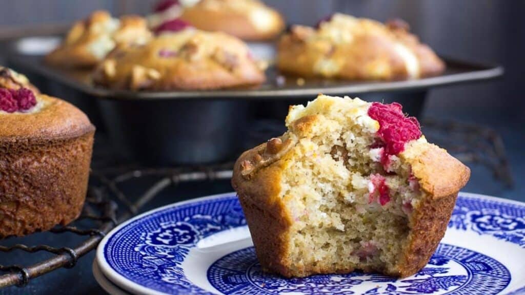 Olive-Oil-Muffins-with-Goat-Cheese-Walnuts-and-Raspberries-on-a-blue-plate-bit-into.