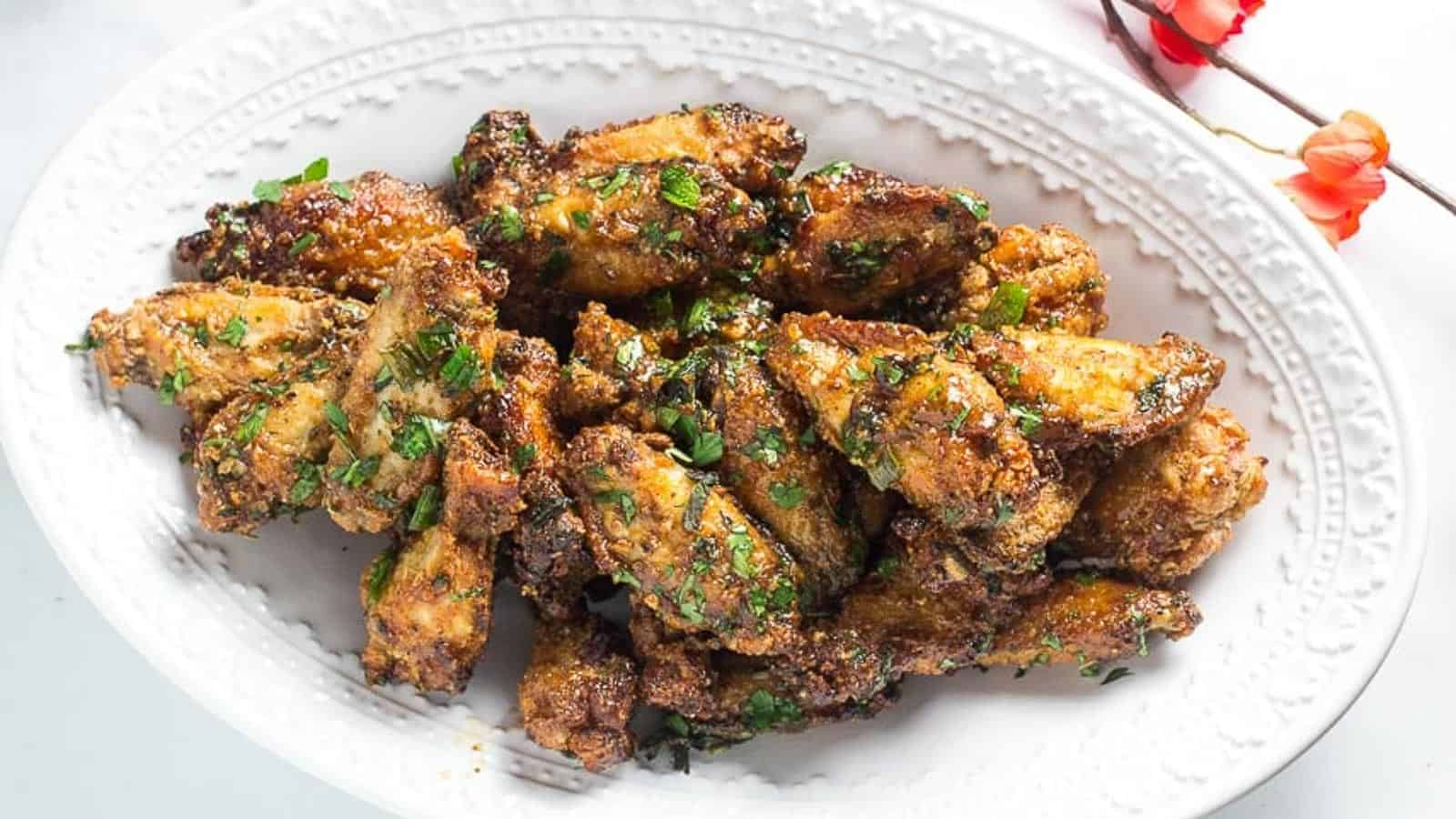 Pok-Pok-Chicken-Wings-on-oval-white-plate-with-coral-colored-flowers-in-background.
