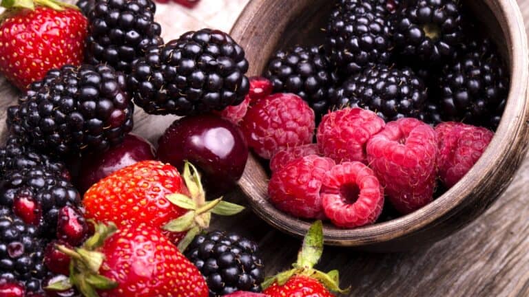 tasty summer fruits on a wooden table. Cherry, Blue berries, strawberry, raspberries, Blackberries, pomegranate