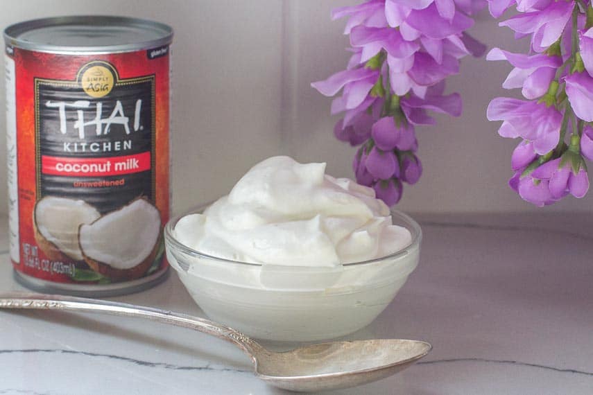 coconut-whipped-cream-in-gladd-bowl-with-spoon-and-can-of-coconut-milk.