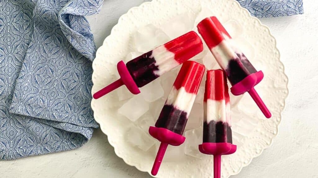 overhead-image-of-vegan-red-white-and-blue-popsicles-on-white-plate.