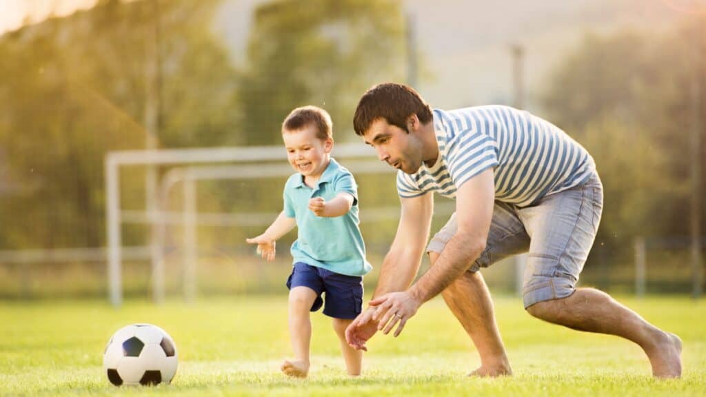 young man father with child playing soccer. 
