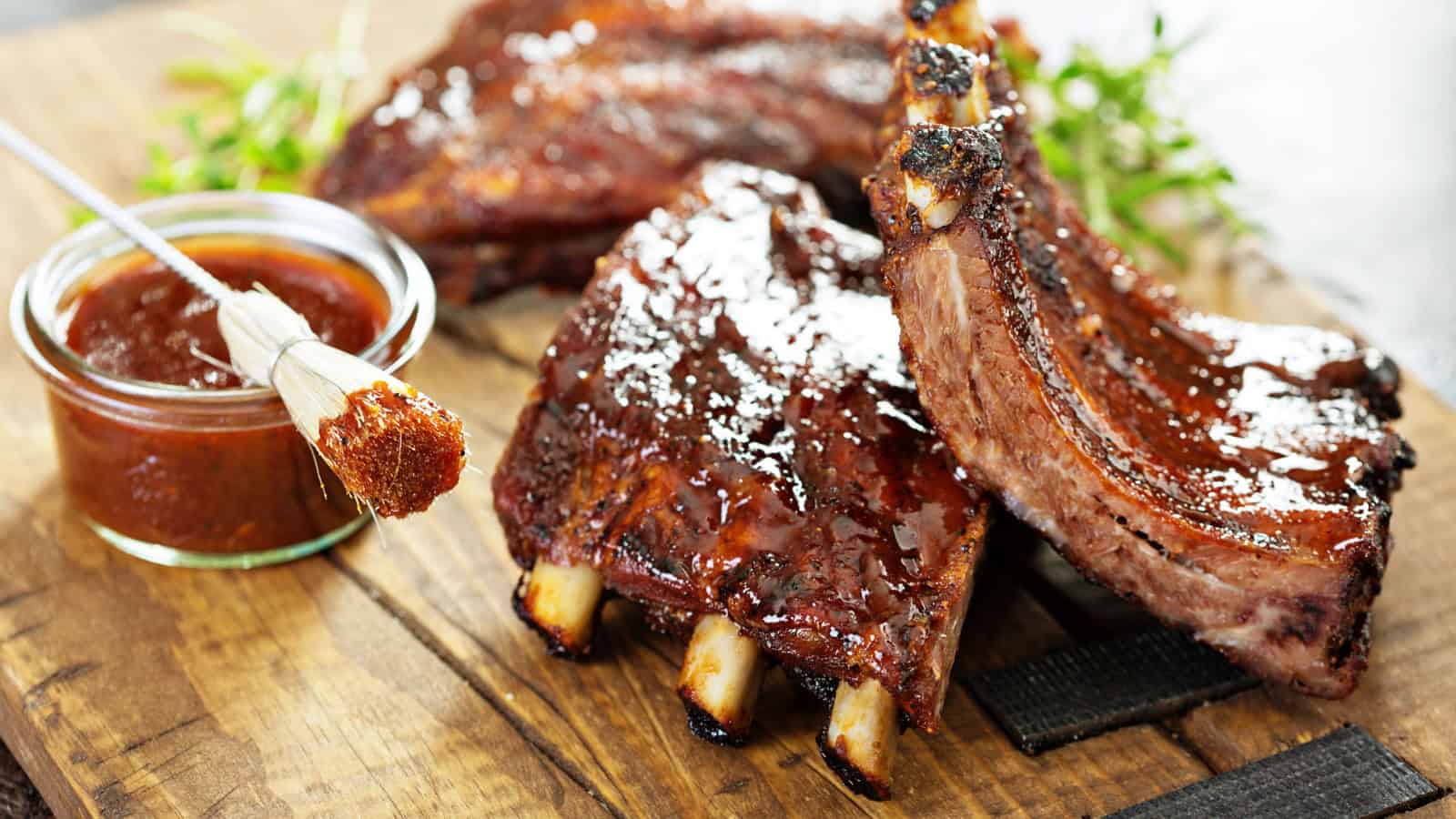 Grilled and smoked ribs with barbeque sauce on a carving board