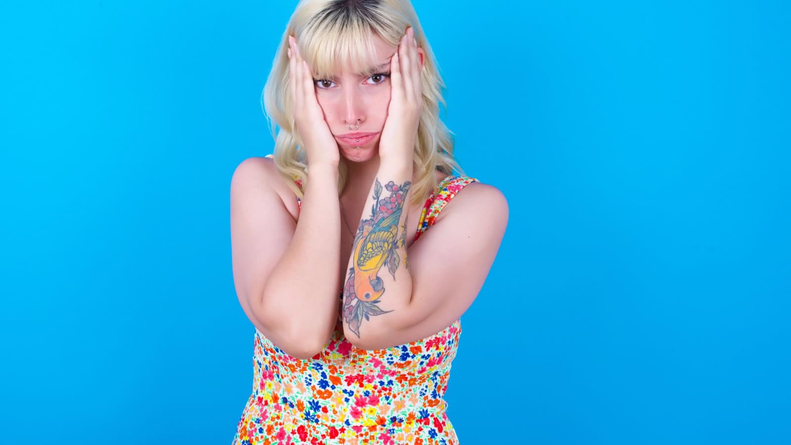 Oh no. Holding head in hands. Woman with tattoos.