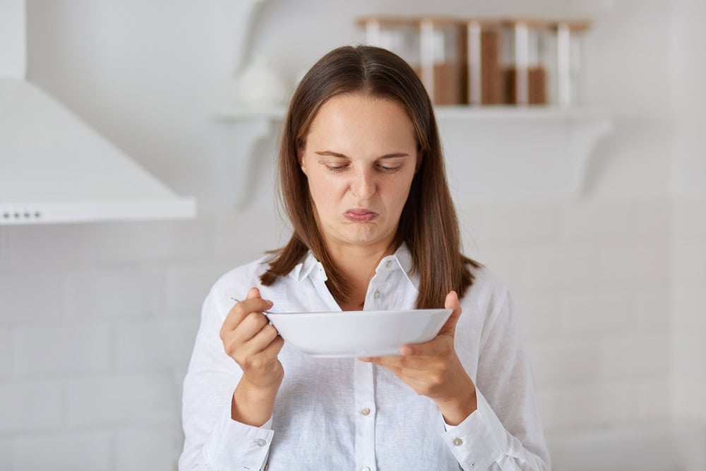 Dark,Haired,Caucasian,Woman,In,White,Shirt,Demonstrates,Disgust,Twisting