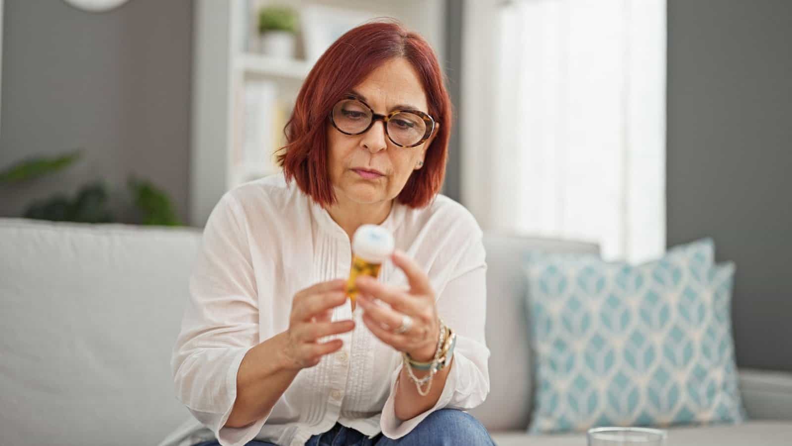 woman reading drug bottle label.