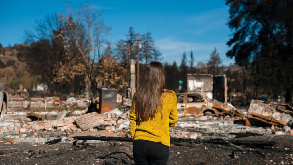 Woman looking at burned house after fire.