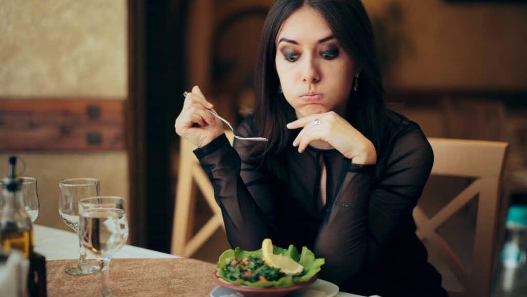 unhappy woman eating salad.