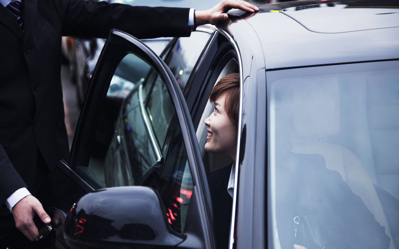 Businessman opening car door for businesswoman