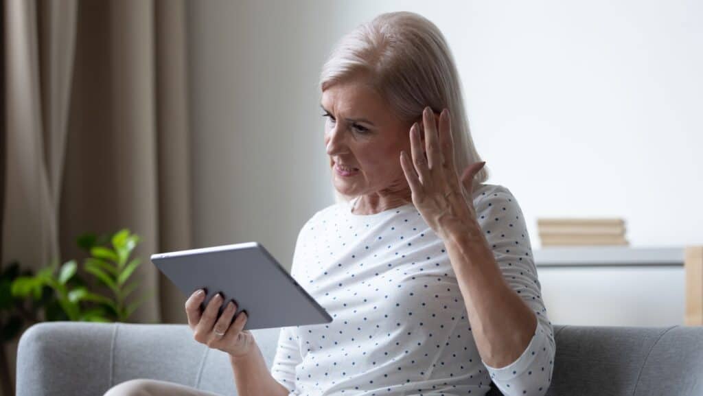 upset senior on tablet.
