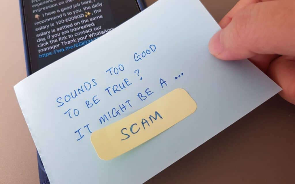 Singapore - October 2023: Scam alert concept. Placing a note with the words Sounds Too Good To Be True It Might Be A Scam on a mobile phone with potential scam message shown on the phone