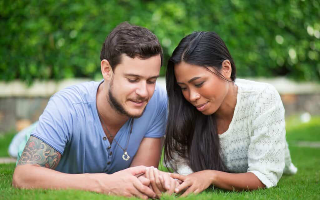 Content Multi-ethnic Couple Resting on Patio Grass