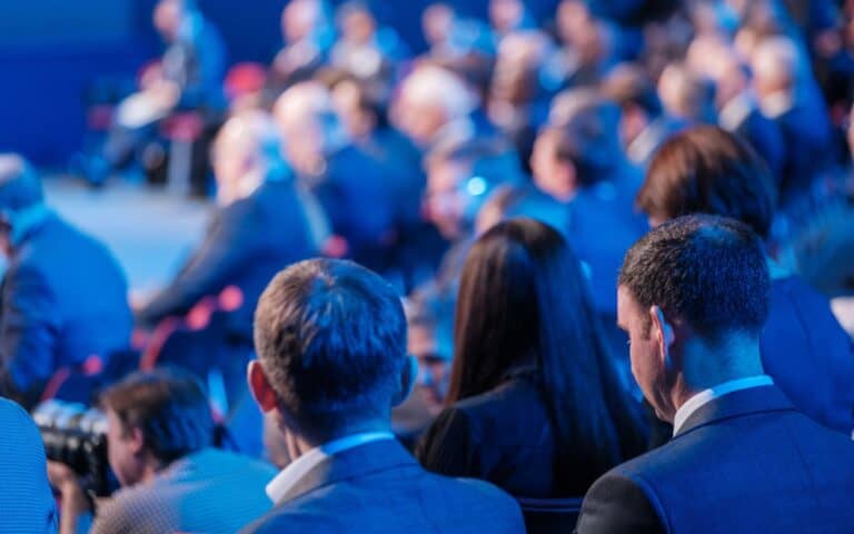 Back view of businessmen attending conference meeting in auditorium at export forum