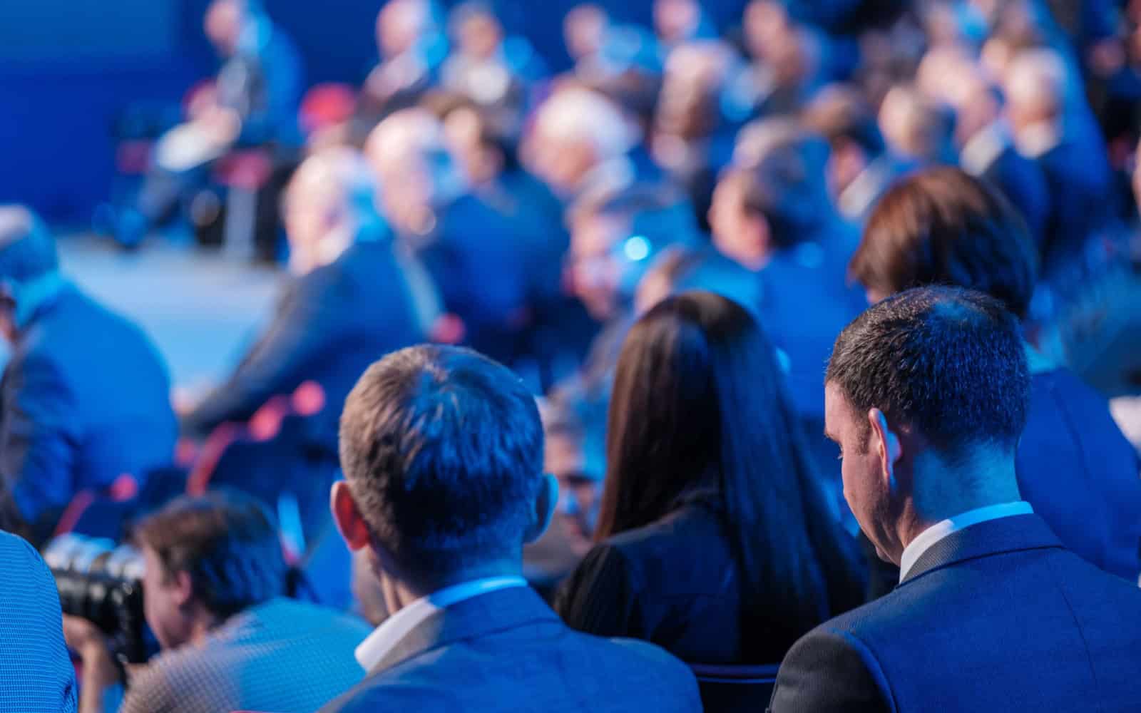 Back view of businessmen attending conference meeting in auditorium at export forum