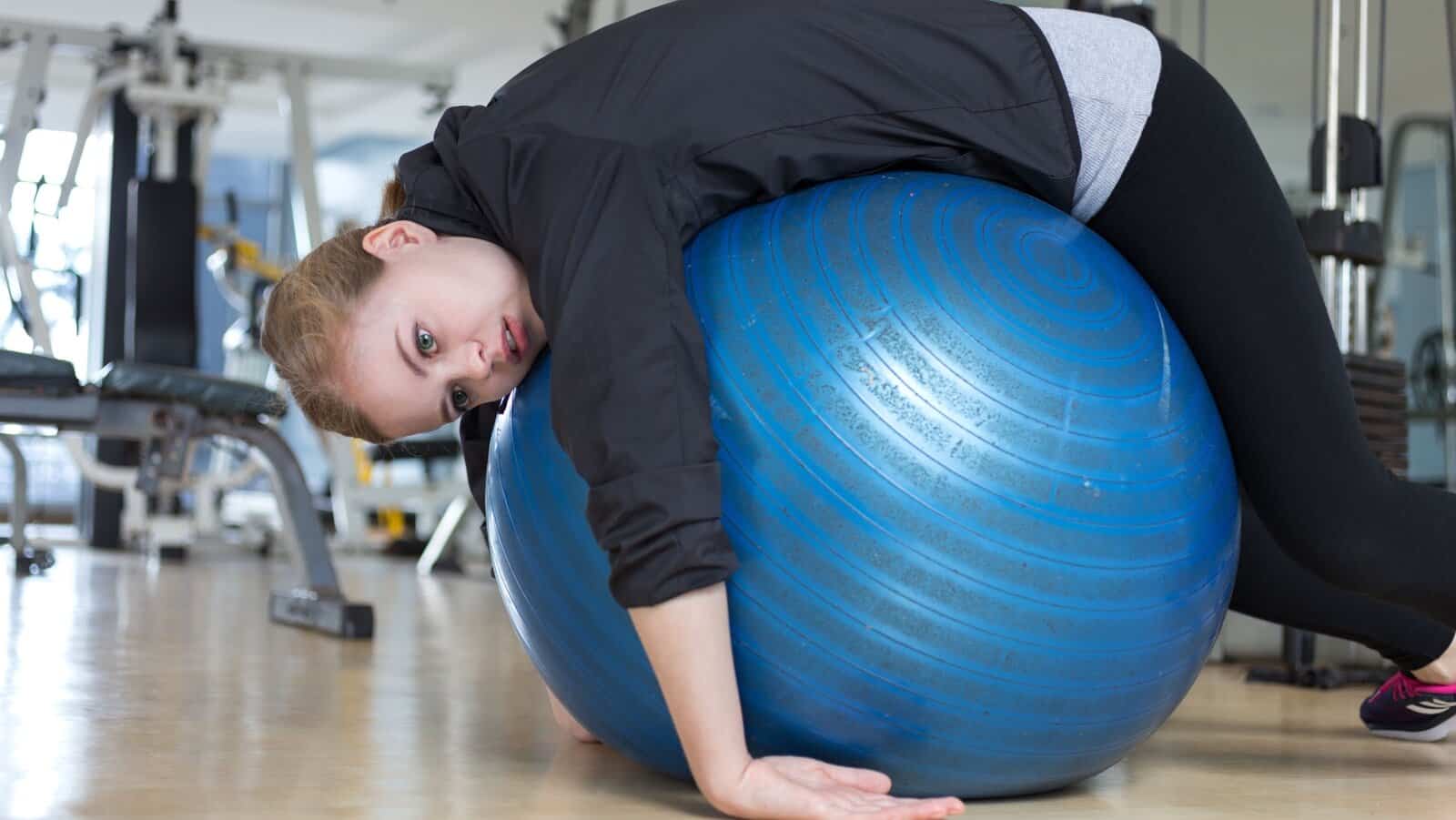 overtraining. woman in gym over a ball