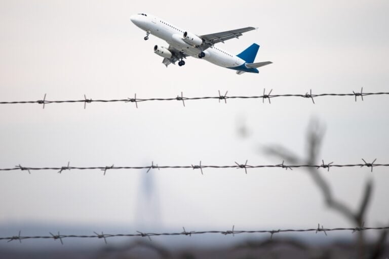 Passenger plane flying behind barbed wire. Aviation idea concept. Deported. International travel. Airplane taking off. Horizontal photo. No people, nobody.